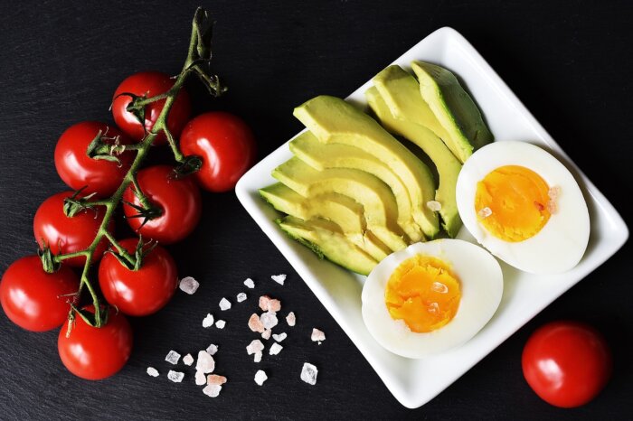 Plates of food with egg, tomatoes and green vegetables that you use eat in a Keto diet style